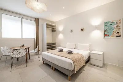 a bedroom with a bed and a table and chairs at 27 VAURTIN - Modern and renovated studio Cannes city centre in Cannes
