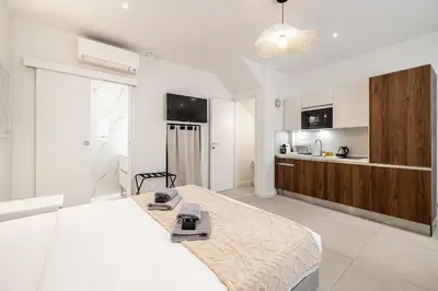 a white bedroom with a large bed and a kitchen at 27 VAURTIN - Modern and renovated studio Cannes city centre in Cannes