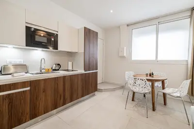 a kitchen with wooden cabinets and a table and chairs at 27 VAURTIN - Modern and renovated studio Cannes city centre in Cannes