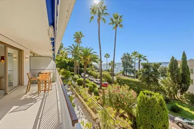 a balcony with a table and chairs and palm trees at 121 MARECHAL - 3-Bedroom Apartment Sea View and Parking in Cannes