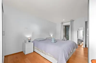 a white bedroom with a white bed and a wooden floor at Luxueux deux pièces - Proche de la mer - FU in Cannes