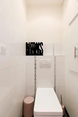 a white bathroom with a toilet and a sign on the wall at Le Grain d'Or YourHostHelper in Cannes