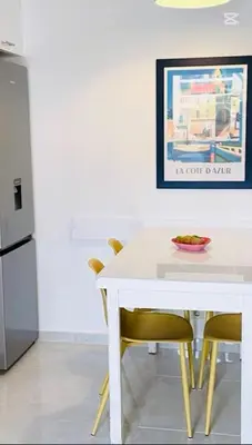 a white dining table with yellow chairs in a kitchen at Appartement bord de mer in Cannes