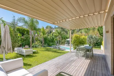 an outdoor deck with a pergola and a yard at 002 Villa Camille in Cannes