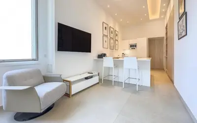 a white living room with a chair and a television at 303 Le Gallia in Cannes