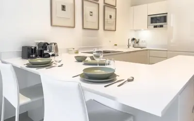 a white kitchen with a table with plates and wine glasses at 303 Le Gallia in Cannes
