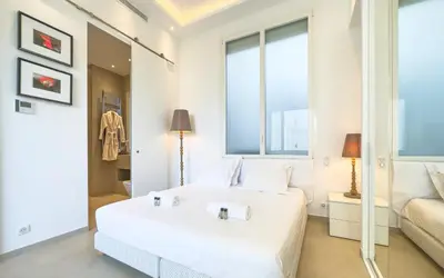 a white bedroom with a large white bed and windows at 303 Le Gallia in Cannes