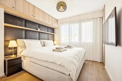 a bedroom with a large white bed and a window at Magnifique appartement à 50 mètres de la Croisette in Cannes