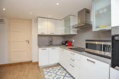 a white kitchen with white cabinets and a door at SUITE DE LUXE MIMOSA 6P in Cannes