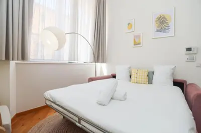 a bedroom with a bed with white sheets and a window at SUITE DE LUXE MIMOSA 6P in Cannes