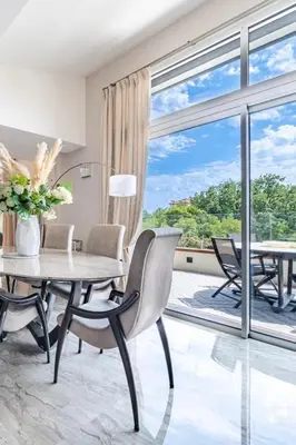 a dining room with a table and chairs and a large window at Oxford-Californie Luxury 4-Bedroom Penthouse With Parking in Cannes