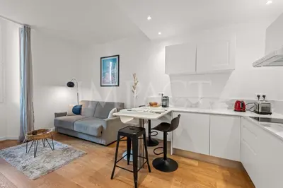 a white kitchen with a table and a couch at REF 2023- Cannes Croisette - Apartment to rent in Cannes