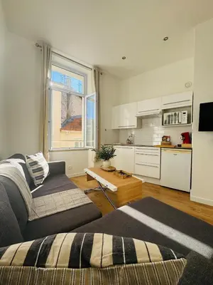 a living room with a couch and a kitchen at Studio Design Climatisé Cœur de Cannes in Cannes