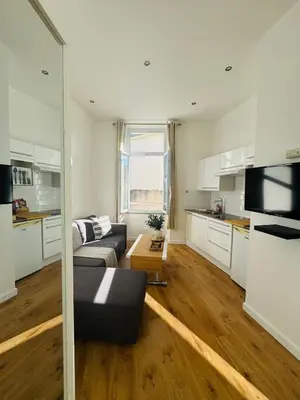 a living room with a couch and a kitchen at Studio Design Climatisé Cœur de Cannes in Cannes
