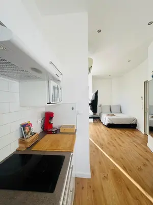 a kitchen and living room with white walls and wooden floors at Studio Design Climatisé Cœur de Cannes in Cannes