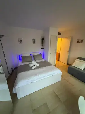 a bedroom with a large white bed with purple lights at Studio Suquet proche palais des festivals congrès in Cannes