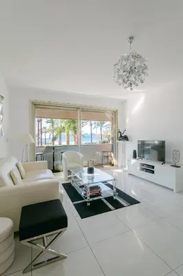 a living room with white furniture and a chandelier at Le Venus in Cannes