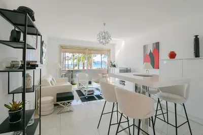 a white kitchen with white chairs and a table at Le Venus in Cannes