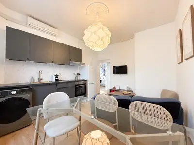 a kitchen and living room with a table and chairs at Stylish 3-Bedroom Cannes Apartment - Steps from Palais des Festivals in Cannes