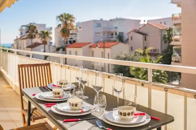 a table on a balcony with glasses and wine glasses at 3 pièces rénové en bord de mer - Terrasse in Cannes