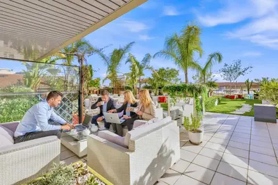 a group of people sitting on a patio with laptops at Jardin d'Eden - Incroyable Rooftop Jardin suspendu in Cannes