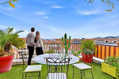a man and woman standing on a balcony with a table and chairs at Jardin d'Eden - Incroyable Rooftop Jardin suspendu in Cannes