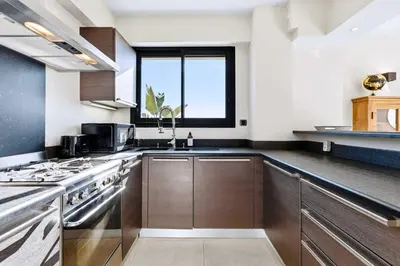 a kitchen with wooden cabinets and a large window at Septieme Ciel - Exceptionnel Appartement vue Mer in Cannes