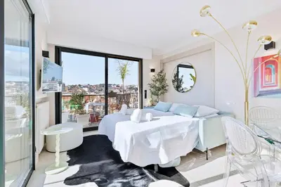 a white bedroom with a bed and a table at Septieme Ciel - Exceptionnel Appartement vue Mer in Cannes