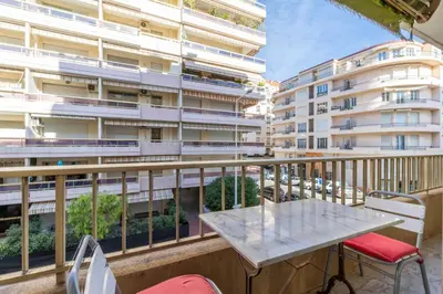 a balcony with a table and chairs and a building at Cozy studio in the heart of Cannes - Near sea in Cannes