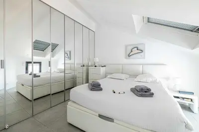 a white bedroom with a large bed and a mirror at Luxury Penthouse 120mÂ² in the heart of Cannes in Cannes
