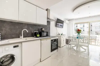 a white kitchen with a sink and a dishwasher at Charming studio near the Croisette in Cannes