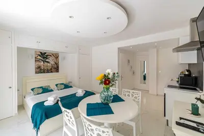 a bedroom with a bed and a table and a kitchen at Charming studio near the Croisette in Cannes