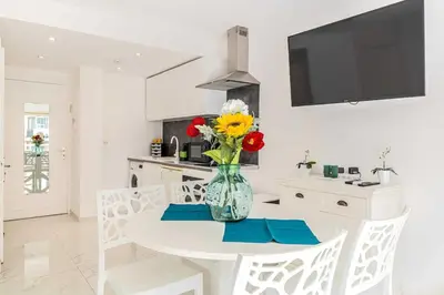 a white kitchen with a vase of flowers on a table at Charming studio near the Croisette in Cannes