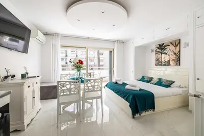 a bedroom with a bed and a table and a kitchen at Charming studio near the Croisette in Cannes