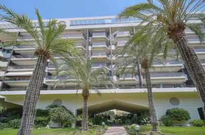 a building with palm trees in front of it at PROCHE CARLTON One bedroom Apartment in Cannes