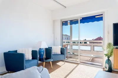 a living room with two blue chairs and a sliding glass door at Marius By Terrys Homes in Cannes