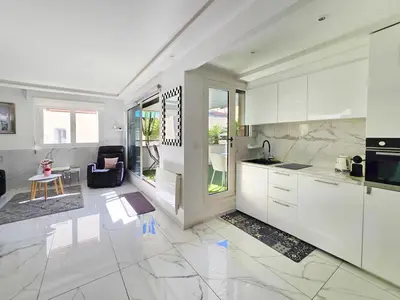 a kitchen with white cabinets and a living room at 51m2 Gray d'Albion, Croisette, terrasse & clim in Cannes