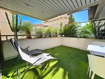 a balcony with a chair and a table and grass at 51m2 Gray d'Albion, Croisette, terrasse & clim in Cannes