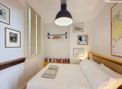 a bedroom with a bed and a lamp and books at 66m2 Cosy appartement avec garage in Cannes