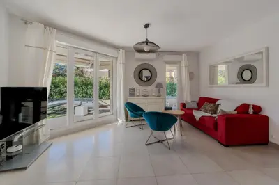 a living room with a red couch and a blue chair at 2P Palm Beach parking, clim et jardin in Cannes