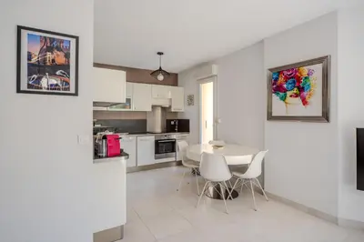 a kitchen with a white table and white chairs at 2P Palm Beach parking, clim et jardin in Cannes