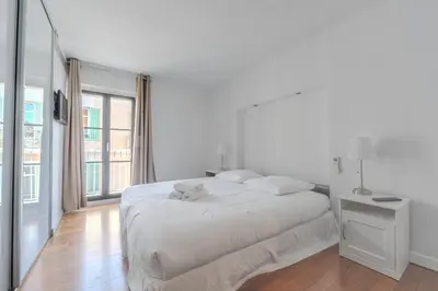 a white bedroom with a large bed with a teddy bear on it at Rue d Antibes 2ch, 2 SDB, clim, balcon in Cannes