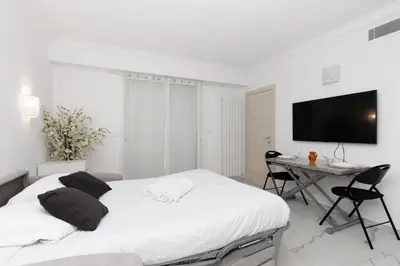 a white bedroom with a bed and a desk at Immogroom - Studio - Sea View - AC in Cannes