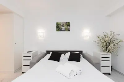 a white bedroom with a large bed with two night stands at Immogroom - Studio - Sea View - AC in Cannes