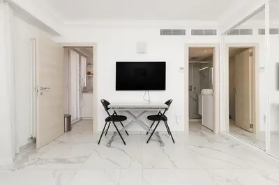 a white room with a table with two chairs and a television at Immogroom - Studio - Sea View - AC in Cannes