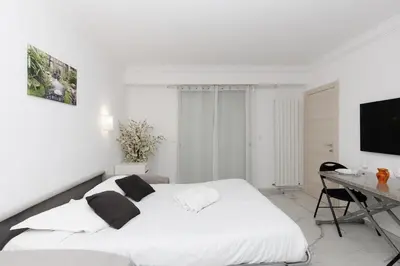a white bedroom with a bed and a desk at Immogroom - Studio - Sea View - AC in Cannes