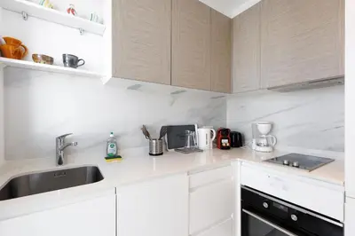 a kitchen with white cabinets and a sink at Immogroom - Studio - Sea View - AC in Cannes