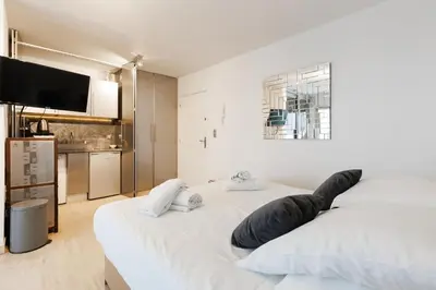 a white bedroom with a large bed and a flat screen tv at Immogroom – Stylish Studio – Beach 1 min away- AC in Cannes