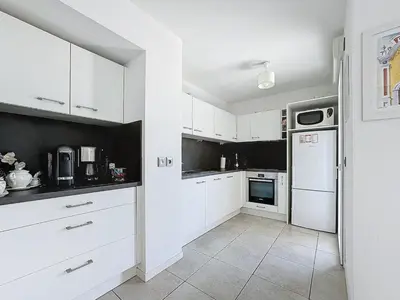 a kitchen with white cabinets and a white refrigerator at Appartement 3 pièces à Cannes avec piscine in Cannes