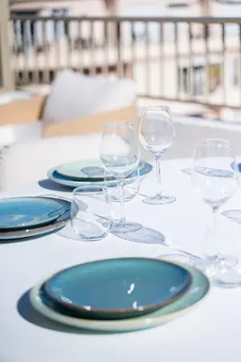 a table with blue plates and wine glasses on it at Terrasse Vue Mer - 2BR - Parking - Croisette 50m in Cannes